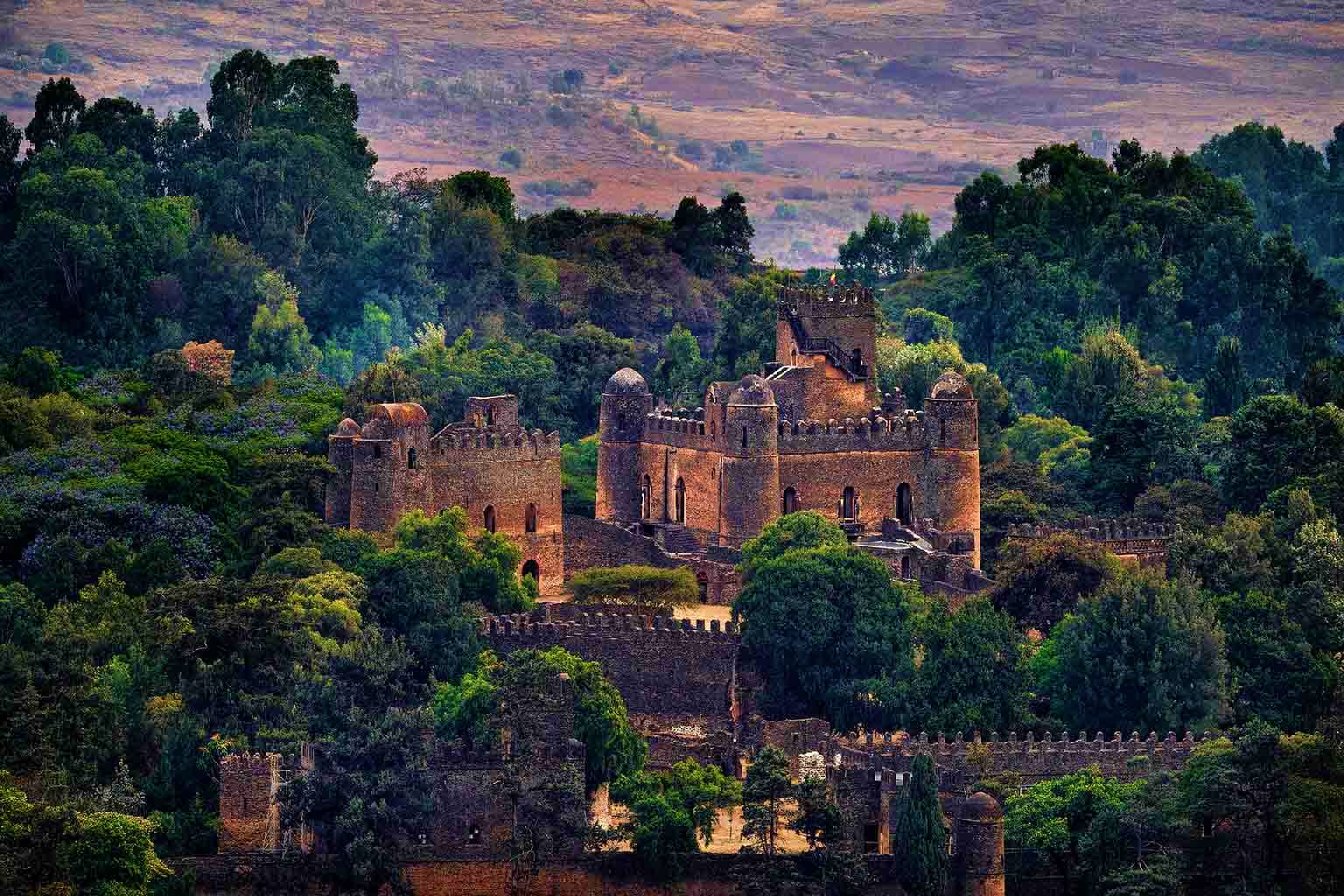 Ethiopia Visa Fasilides Castle surrounded by lush green forest and terraced agricultural hills in Gondar, Ethiopia
